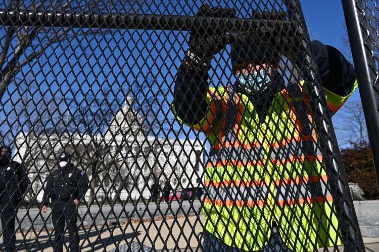 Workers put up fencing outside the U.S. Capitol on Jan. 7, a day after the violent insurrection. 