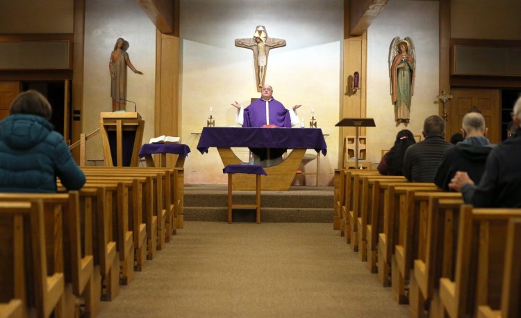 The Rev. Philip Tracy celebrates Mass at Holy Martyrs Church in Falmouth on Thursday. Bishop Robert Deeley of the Roman Catholic Diocese of Portland called the governor's updated order limiting the number of people in churches "unacceptable." 