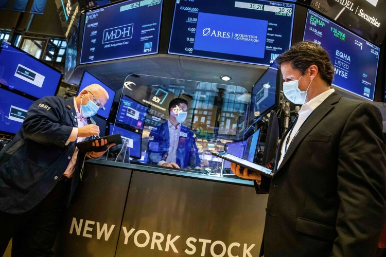 Specialist Thomas McArdle, center, works with traders on the floor  of the New York Stock Exchange on Tuesday. Stocks were broadly higher in afternoon trading, but shares of closely watched companies like GameStop and AMC Entertainment were falling sharply. 