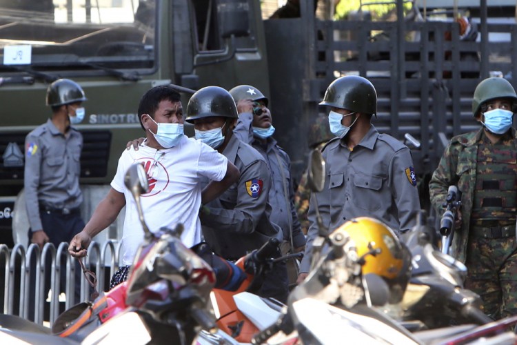 A man is held by police during a crackdown on anti-coup protesters holding a rally in front of the Myanmar Economic Bank in Mandalay, Myanmar on Monday. Soldiers and police attacked protesters with sticks and local media reported that rubber bullets were fired into the crowd. Police also were seen pointing guns toward protesters.