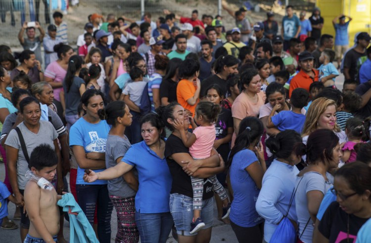Migrants, many of whom were returned to Mexico under the Trump administration's "Remain in Mexico" policy, wait in line to get a meal in an encampment near the Gateway International Bridge in Matamoros, Mexio on Aug. 30, 2019. The Biden administration on Friday announced plans for tens of thousands of asylum-seekers waiting in Mexico for their next immigration court hearings to be released in the United States while their cases proceed. 