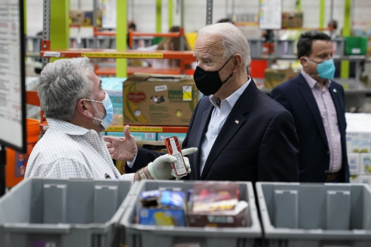 President Biden talks with a volunteer at the Houston Food Bank on Friday in Houston.