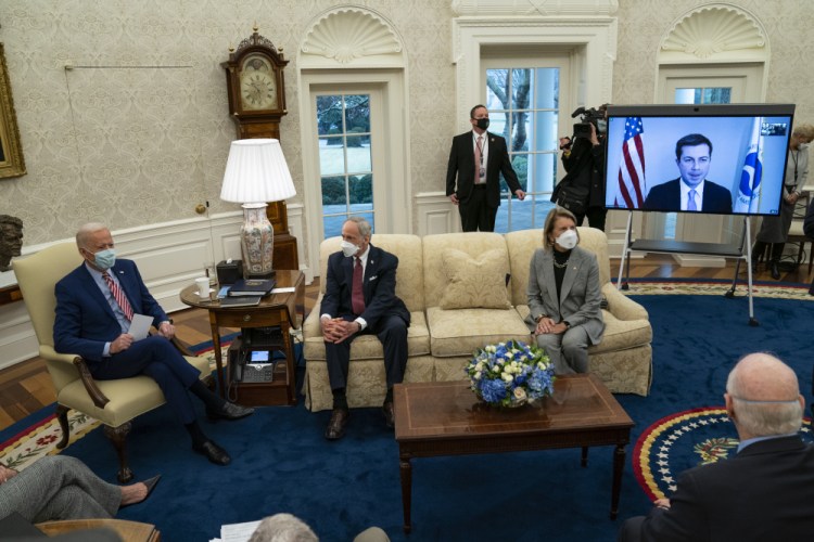 President Biden speaks during a meeting with lawmakers on investments in infrastructure, in the Oval Office of the White House on Thursday in Washington. From left, Biden, Sen. Tom Carper, D-Del., Sen. Shelley Moore Capito, R-W.Va., and Transportation Secretary Pete Buttigieg, on screen. 