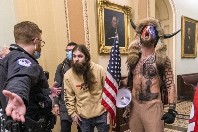 Supporters of President Trump, including Jacob Chansley, right with fur hat, are confronted by U.S. Capitol Police officers outside the Senate Chamber inside the Capitol in Washington during the insurrection on Jan. 6.