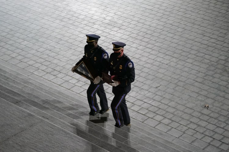 An honor guard carries an urn with the cremated remains of U.S. Capitol Police officer Brian Sicknick and folded flag up the steps of the U.S Capitol to lie in honor in the Rotunda on Tuesday in Washington. 