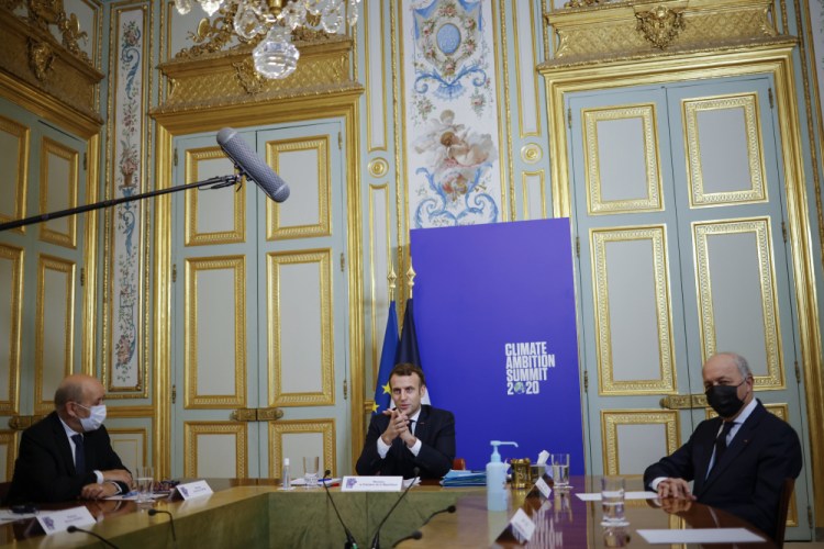 FILE - In this Dec. 12, 2020, file photo, French President Emmanuel Macron, center flanked by French Foreign Minister Jean-Yves Le Drian, left, and President of the French Constitutional Council Laurent Fabius, right, speaks during the Climate Ambition Summit 2020 video conference at the Elysee Palace in Paris. World leaders are applauding Friday's formal return of the U.S. to the mostly voluntary 2015 agreement.