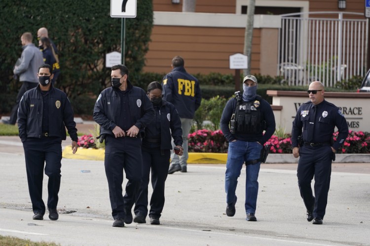 Law enforcement officers walk near the entrance to an apartment complex where a shooting killed or wounded several FBI agents serving an arrest warrant, Tuesday, Feb. 2, in Sunrise, Fla. 