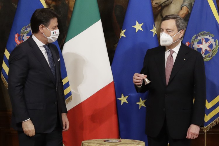 Italian outgoing Premier Giuseppe Conte hands over the Cabinet minister bell to new Premier Mario Draghi during a ceremony at Chigi Palace in Rome on Saturday.
