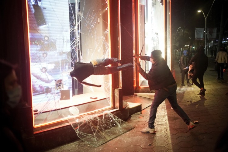 A demonstrator smashes a shop window during a protest condemning the arrest of rap singer Pablo Hasél in Barcelona, Spain, on Saturday.

