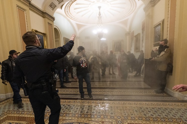 Smoke fills the walkway outside the Senate Chamber on Jan. 6 as insurrectionists loyal to President Donald Trump are confronted by U.S. Capitol Police officers inside the U.S. Capitol. Arguments begin Tuesday in the impeachment trial of Trump on allegations that he incited the violent mob that stormed the U.S. Capitol on Jan. 6. (AP Photo/Manuel Balce Ceneta, File)