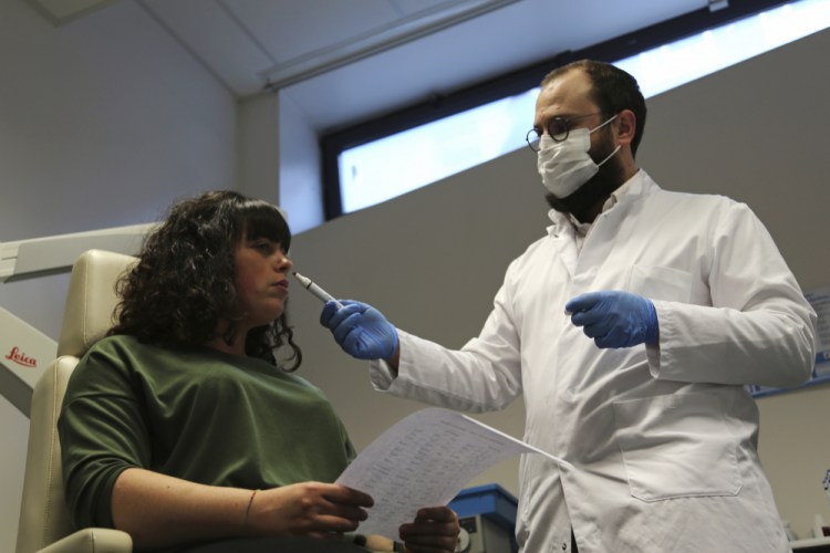 Dr. Clair Vandersteen, right, wafts a tube of odors under the nose of a patient, Gabriella Forgione, during tests in a hospital in Nice, southern France, this month  to help determine why she has been unable to smell or taste since she contracted COVID-19 in November 2020.  