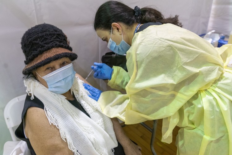 Registered Nurse Rita Alba gives a patient the first dose of coronavirus vaccine at a pop-up vaccination site at the Bronx River Community Center on Sunday in New York City. The U.S. is averaging about 1.3 million shots a day. 