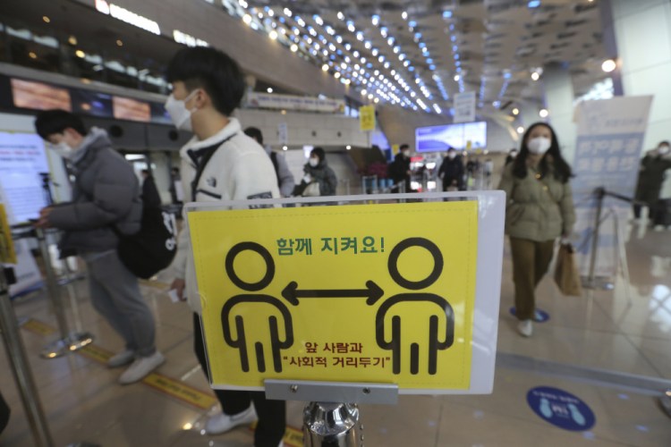 A social distancing sign is seen as passengers wait to board planes on the eve of Lunar New Year holiday at the domestic flight terminal of Gimpo airport in Seoul, South Korea, Thursday, Feb. 11, 2021. The signs read: "Keep together." 