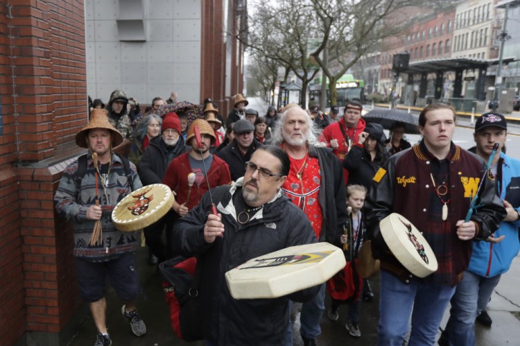 Tony A. "Naschio" Johnson, center, elected chairman of the Chinook Indian Nation, plays a drum as he leads tribal members and supporters as they march to the federal courthouse in Tacoma, Wash., on Jan. 6, 2020.