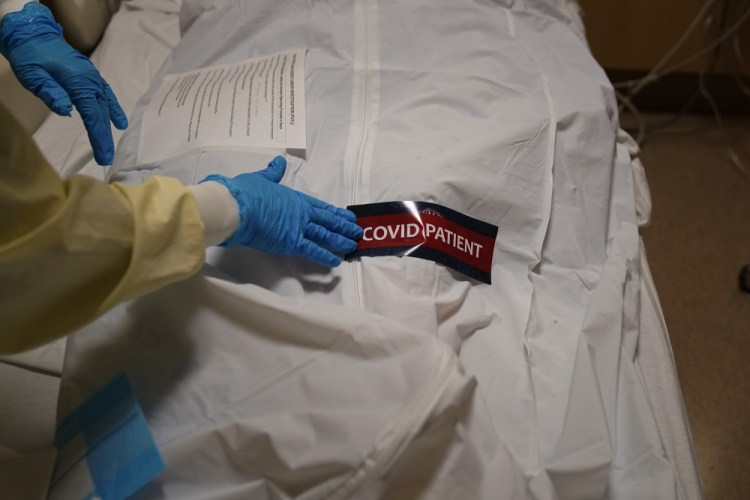 A hospital worker places a "COVID Patient" sticker on a body bag holding a deceased patient Jan. 9 at Providence Holy Cross Medical Center in the Mission Hills section of Los Angeles.