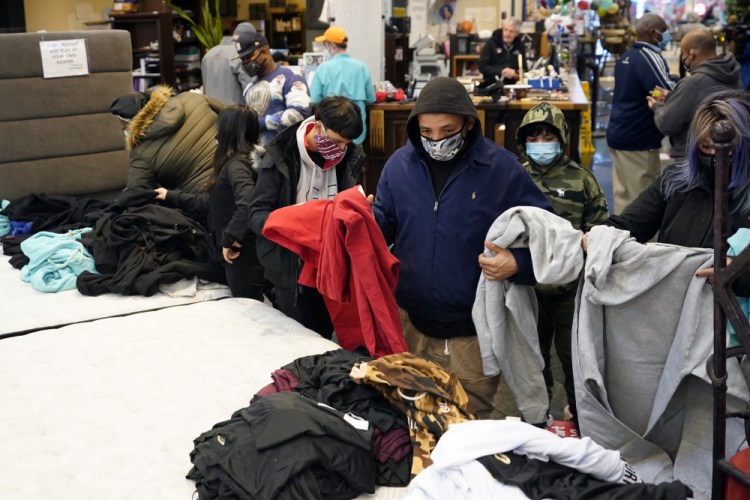 People select shirts and sweatshirts being given away at a Gallery Furniture store Tuesday after the owner opened his business as a shelter for those without power at their homes in Houston. 

