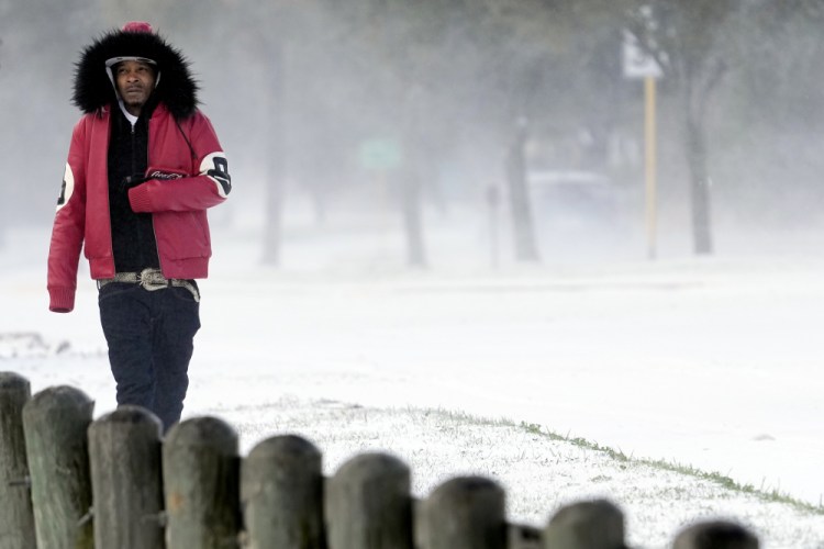 Igee Cummings walks through the snow Monday, Feb. 15, in Houston. A winter storm dropping snow and ice sent temperatures plunging across the southern Plains, prompting a power emergency in Texas a day after conditions canceled flights and impacted traffic across large swaths of the U.S. 