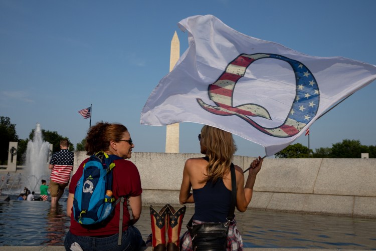 Supporters of the extremist ideology QAnon wait for a Fourth of July military flyover at the World War II Memorial in D.C. last year. 