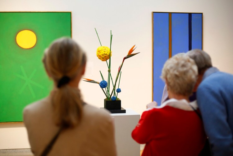 PORTLAND, ME - FEBRUARY 13: Visitors study the floral design by Alora Carrier, Layne Gregory and and Sabrina Warner of St. Mary's Garden Club, inspired by Green Ground, a 1968 painting by Adolph Gottlieb, during a tour of Art in Bloom at Portland Museum of Art. (Staff photo by Derek Davis/Staff Photographer)