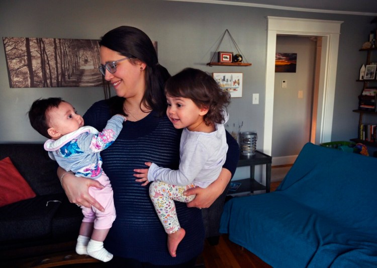 Abby Howell of Biddeford holds her children, 4-month-old Audrey, left, and Eloise Garafalo, 2, at their home on Thursday. Howell is one of thousands of Maine women who've had to leave jobs or are having trouble finding work because of child and family care pressures related to the pandemic and recession.