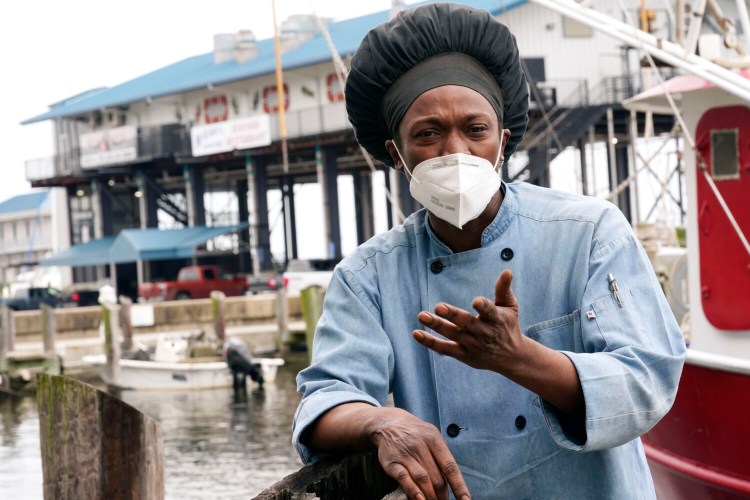 Leo Carney, kitchen manager at McElroy's Harbor House in Biloxi on the Mississippi Gulf Coast, stands along the dock at the city's small craft harbor on Friday, March 5, 2021, as he speaks about his belief that the removal of coronavirus restrictions will disproportionately impact Black residents — many of whom are essential workers. Carney said he would feel better with restrictions being removed if essential workers had access to the coronavirus vaccine. (AP Photo/Rogelio V. Solis)
