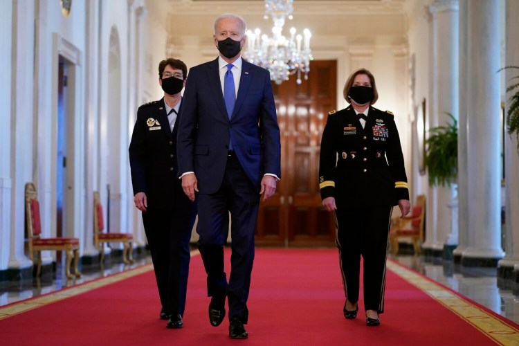 President Biden walks with U.S. Air Force Gen. Jacqueline Van Ovost, left, and U.S. Army Lt. Gen. Laura Richardson before speaking at an event to mark International Women's Day on Monday in the East Room. One of former Education Secretary Betsy DeVos' changes was the narrowing of the definition of sexual harassment – one of the policies under Biden's review.