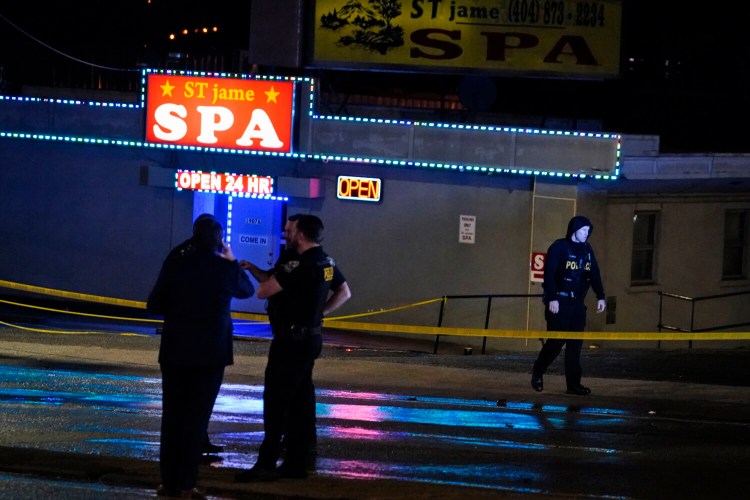 Law enforcement  confers outside a massage parlor following a shooting on Tuesday in Atlanta. 