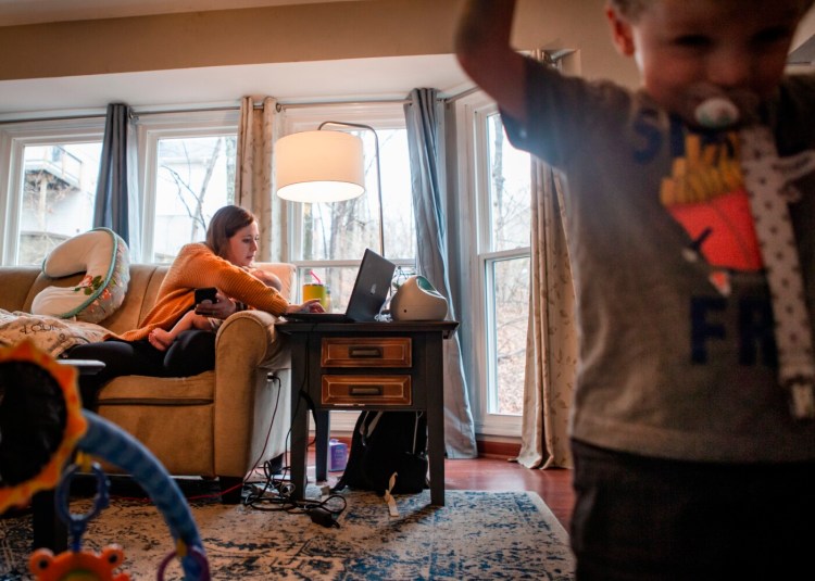 Dr. Elizabeth Bergamini,  pediatrician in suburban St. Louis, searches online for open COVID-19 vaccine appointments while holding her 4-month-old son, Louis, and supervising her 2-year-old son, James Jerome, at her home in Wildwood, Mo., on March 11. Bergamini drove about 30 people to often out-of-the way vaccination events after the state opened eligibility to those 65 and older. 