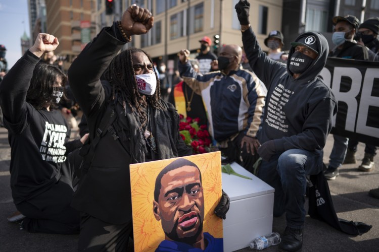 Cortez Rice, left, of Minneapolis, sits with others in the middle of Hennepin Avenue on Sunday, March 7, in Minneapolis, Minn., to mourn the death of George Floyd a day before jury selection is set to begin in the trial of former Minneapolis officer Derek Chauvin, who is accused of killing Floyd. 