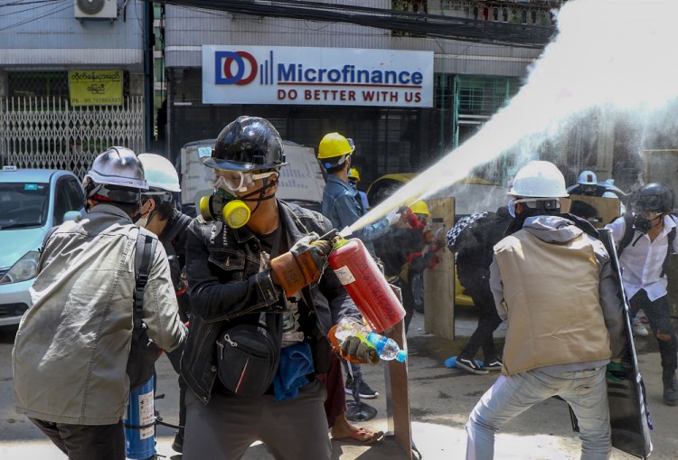 Anti-coup protesters discharge fire extinguishers to counter the impact of the tear gas fired by police during a demonstration Thursday in Yangon.