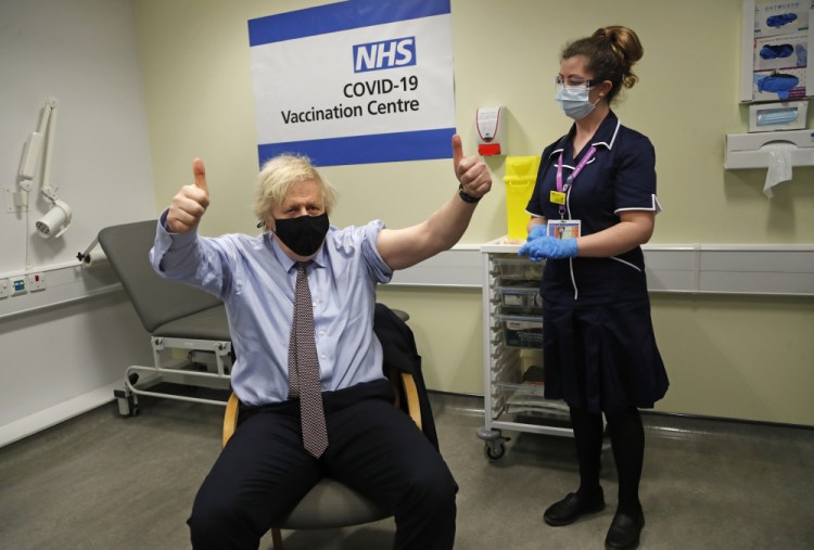 Britain's Prime Minister Boris Johnson gestures after receiving the first dose of the AstraZeneca vaccine administered by nurse and Clinical Pod Lead, Lily Harrington at St.Thomas' Hospital in London, Friday, March 19. 