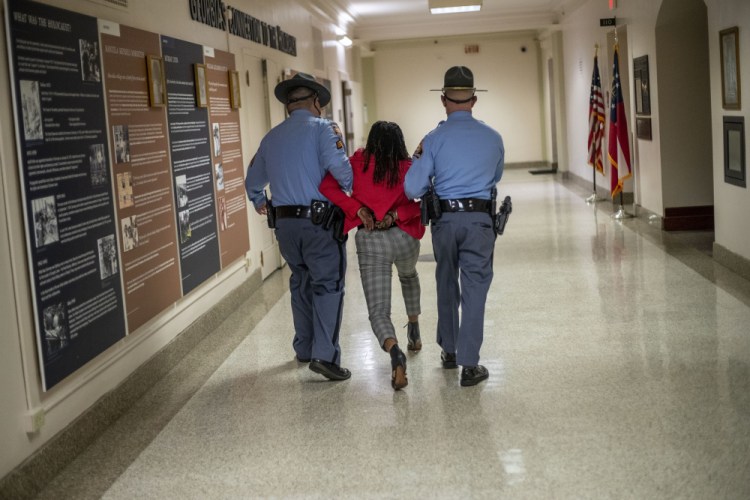 Georgia Rep. Park Cannon, D-Atlanta, is escorted out of the Georgia Capitol by Georgia state troopers after being asked to stop knocking on a door that lead to Gov. Brian Kemp’s office while Kemp was speaking after signing a sweeping overhaul of state elections behind closed doors in Atlanta on Thursday. An attorney for Cannon says it’s “law enforcement overreach” to charge the Georgia House member with two felonies. 