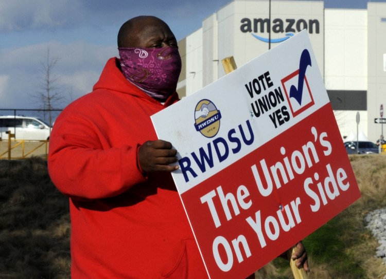 Michael Foster of the Retail, Wholesale and Department Store Union holds a sign outside an Amazon facility where labor is trying to organize workers on Tuesday, Feb. 9. For Amazon, a successful effort could motivate other workers to organize. 
