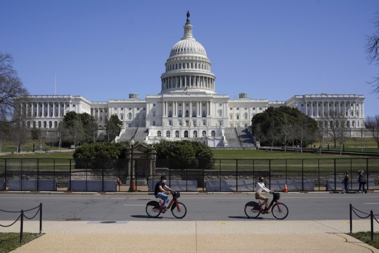 Bicyclists ride past an inner perimeter of security fencing on Capitol Hill in Washington on Sunday, after portions of an outer perimeter of fencing were removed overnight to allow public access. 