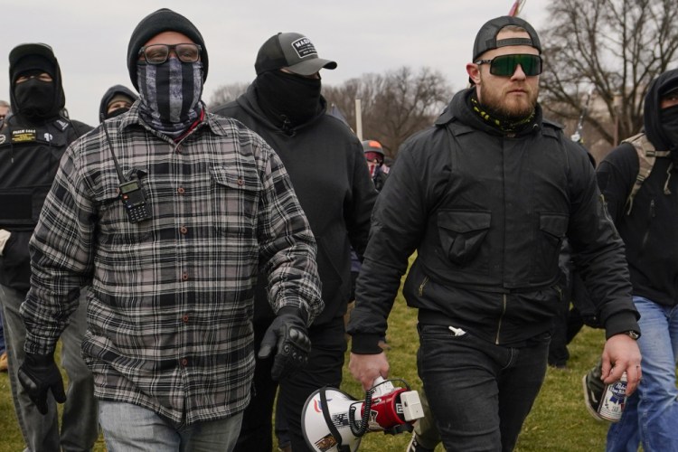 Proud Boy members Joseph Biggs, left, and Ethan Nordean, right, with megaphone, walk toward the U.S. Capitol in Washington, in support of President Trump on Jan. 6. They are charged with, among other things,  conspiring to impede Congress' certification of the Electoral College vote.  