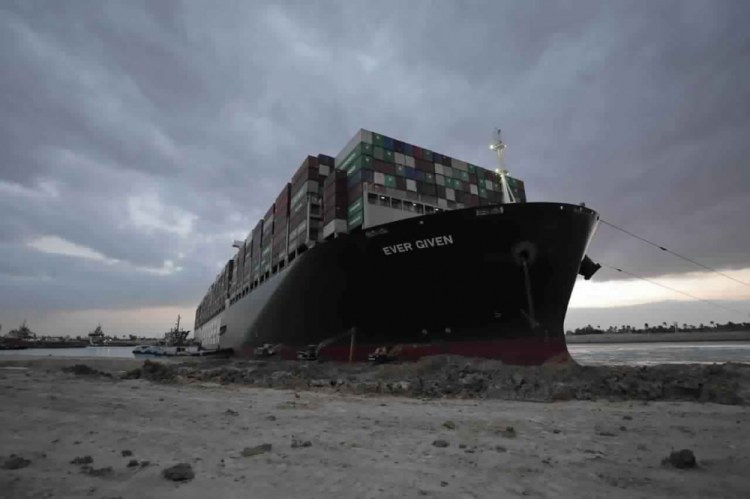 In this photo released by the Suez Canal Authority, tug boats and diggers work to free the Panama-flagged, Japanese-owned Ever Given, which is lodged across the Suez Canal, Sunday, March 28, 2021. Two additional tugboats are speeding to canal to aid efforts to free the skyscraper-sized container ship wedged for days across the crucial waterway. That's even as major shippers increasingly divert their boats out of fear the vessel may take even longer to free. 
