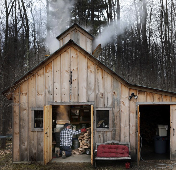 Jason Landry loads wood into the firebox as he boils down sap at his sugar house to make maple syrup March 10, 2016, in Loudon, N.H.