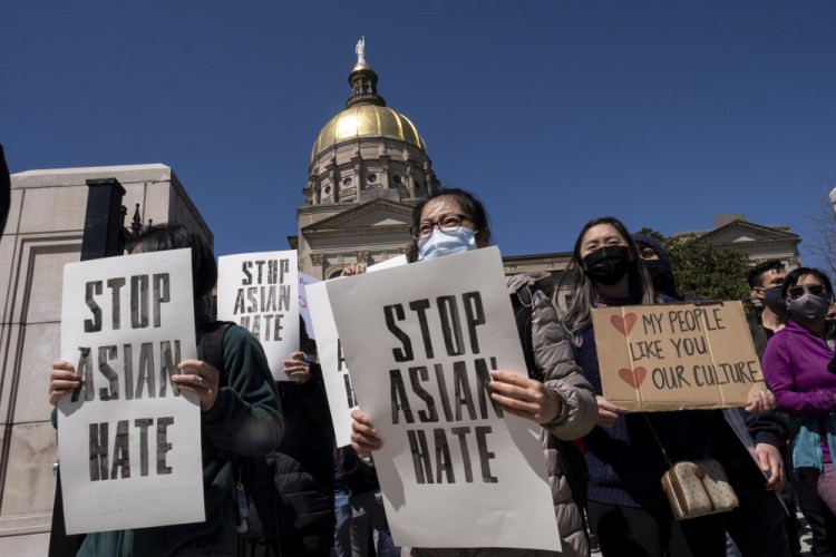 People hold signs while participating in a "stop Asian hate" rally outside the Georgia State Capitol in Atlanta on Saturday afternoon, March 20. 