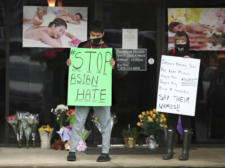 After dropping off flowers Jesus Estrella, left, and Shelby stand in support of the Asian and Hispanic community outside Young's Asian Massage in Acworth, Ga. The murder case against Robert Aaron Long, a white man accused of shooting and killing six women of Asian descent and two other people at Atlanta-area massage businesses, could become the first big test for Georgia’s new hate crimes law.