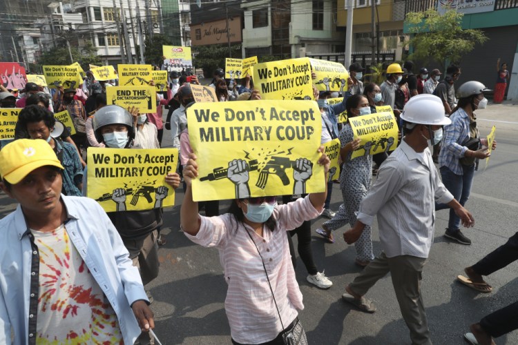 Anti-coup demonstrators display signs during a protest against the military coup in Mandalay, Myanmar, on Monday. Myanmar's ruling junta has declared martial law in parts of the country's largest city as security forces killed more protesters in an increasingly lethal crackdown on resistance to last month's military coup. 