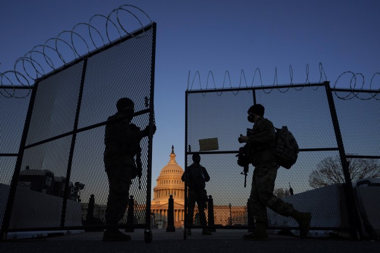 National Guard soldiers open a gate in the razor wire-topped perimeter fence around the U.S. Capitol to allow a colleague in at sunrise in Washington on Monday.