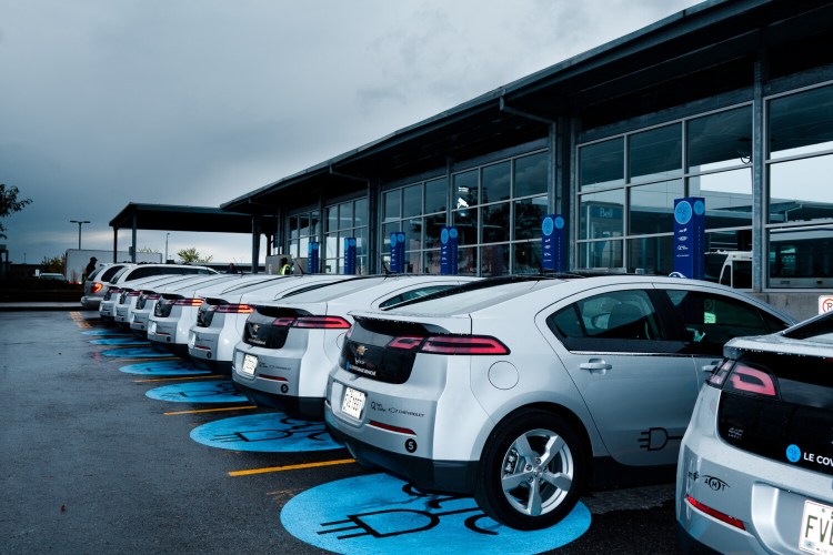 A fleet of Chevy Volt plug-in vehicles are parked in charging spaces outside a government agency in Quebec.