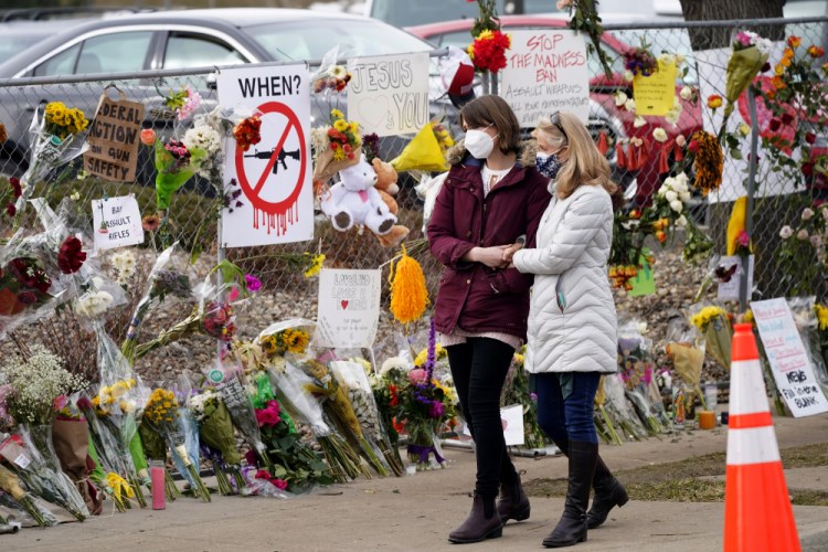 Mourners walk along the temporary fence put up around the parking lot of a King Soopers grocery store Thursday, where a mass shooting took place earlier in the week in Boulder, Colo. 