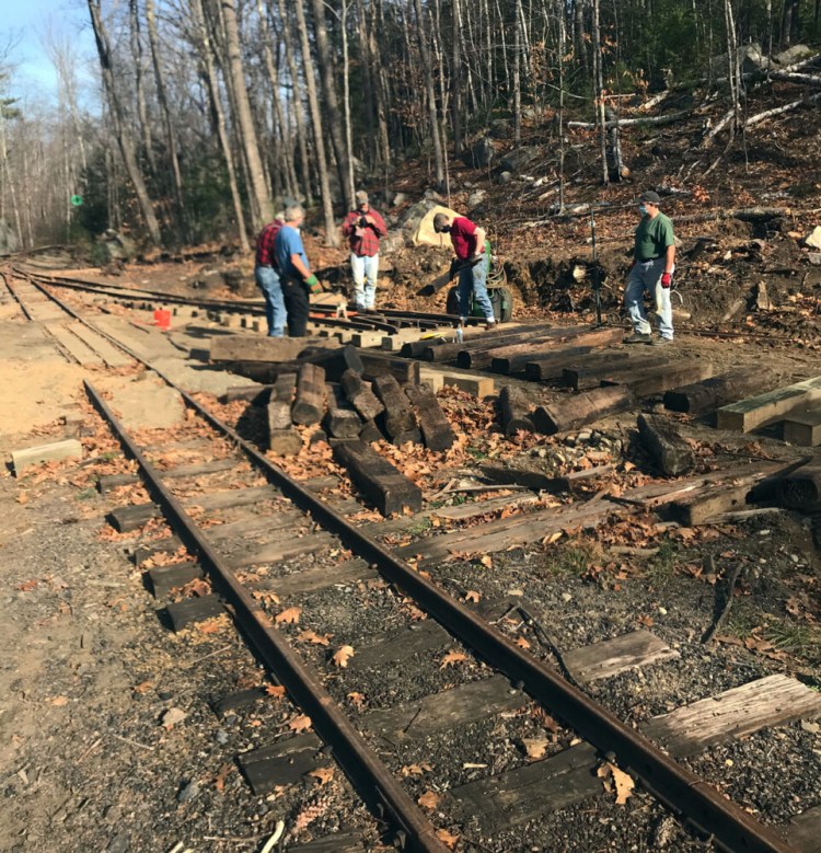 Sandy River and Rangeley Lakes Railroad  and Wiscasset, Waterville and Farmington Railway volunteers work together to lay track on Nov. 7, 2020 in Phillips. 