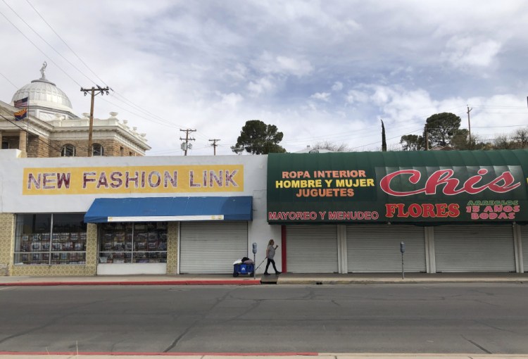 A woman walks past two out-of-business clothing stores located steps away from the U.S.-Mexico border on Monday in Nogales, Ariz. 

