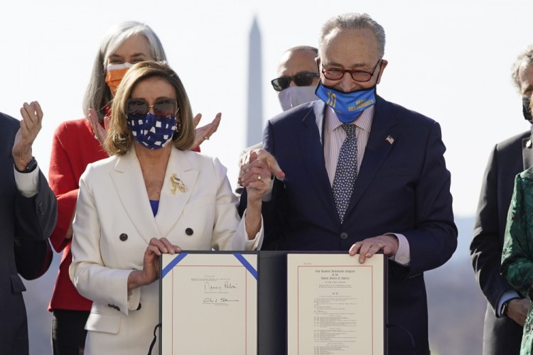 House Speaker Nancy Pelosi of California and Senate Majority Leader Chuck Schumer of New York finish signing the $1.9 trillion COVID-19 relief bill during an enrollment ceremony on Capitol Hill on Wednesday in Washington.