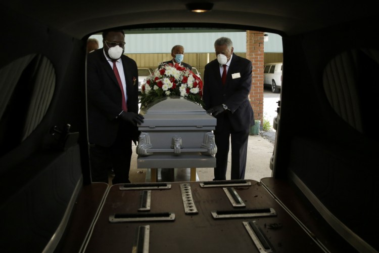 Mortician Cordarial O. Holloway, foreground left, funeral director Robert L. Albritten, foreground right, place a casket into a hearse in Dawson, Ga., on April 18.