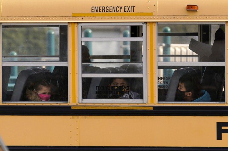 Elementary school students sit on board a school bus after attending in-person classes at school in Wheeling, Ill. in November 2020. The latest federal relief package includes $81 billion that began flowing to states in late March 2021 with the goal of helping schools reopen quickly. 