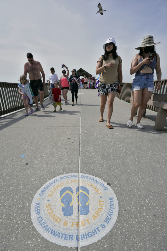 Visitors walk on the pier near a social distancing sticker over Clearwater Beach on Tuesday, March 2, in Clearwater, Fla., a popular spring break destination west of Tampa. 