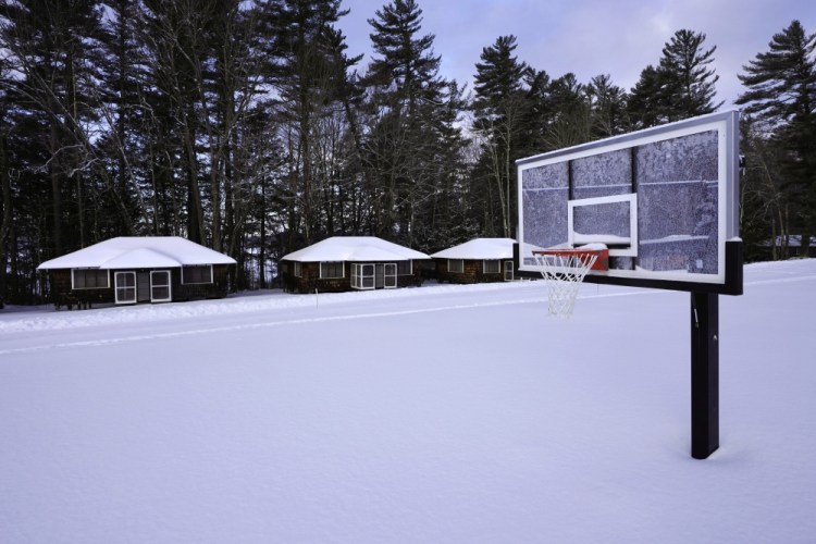 Snow covers a basketball court at Camp Fernwood, a summer camp for girls, last month in Poland, Maine. Camp directors across the country are feeling more confident about reopening this summer after a pandemic hiatus in 2020, but in some states they are still awaiting guidelines.